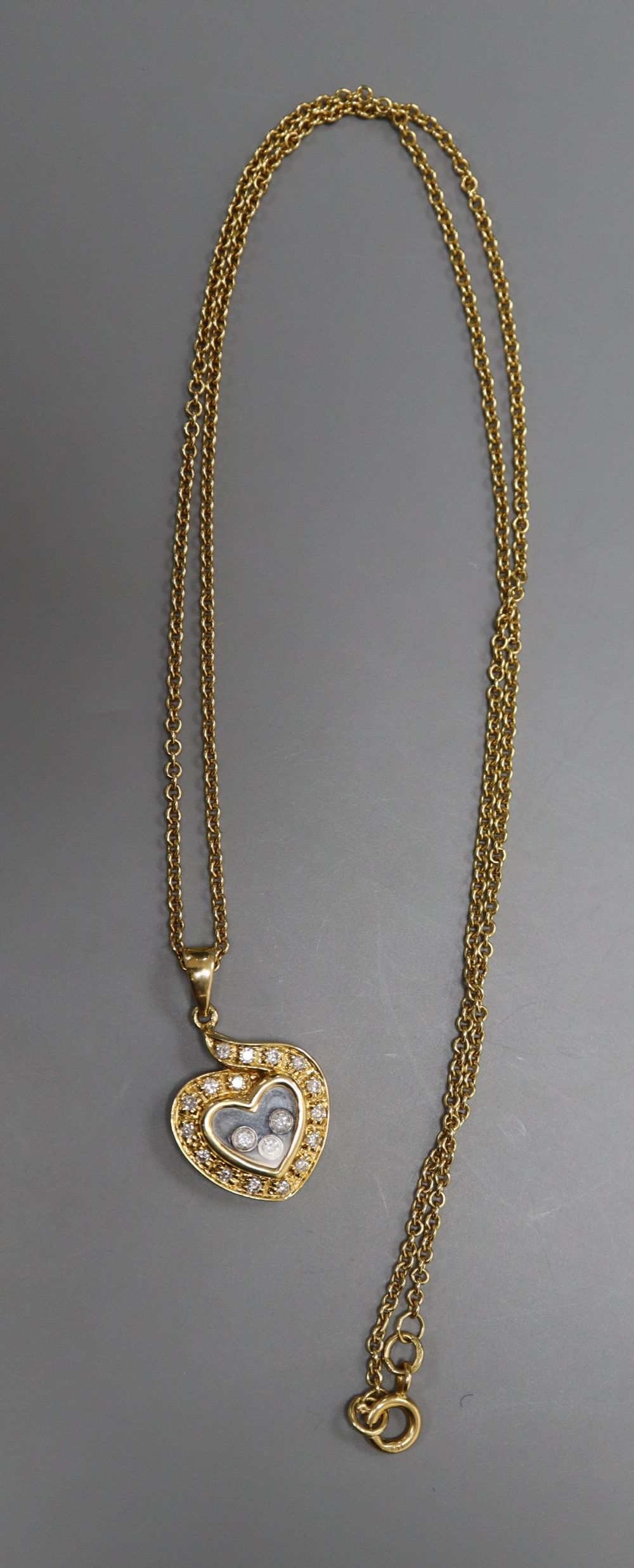 A modern Chopard style 18k and floating diamond set heart shaped pendant, on a 750 chain, pendant 18mm, gross 8.3 grams.